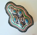 Agate-like rock with colorful concentric layers on a white background