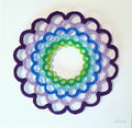 Decorative circular design with concentric rings in purple, blue, green, and white on a white background.