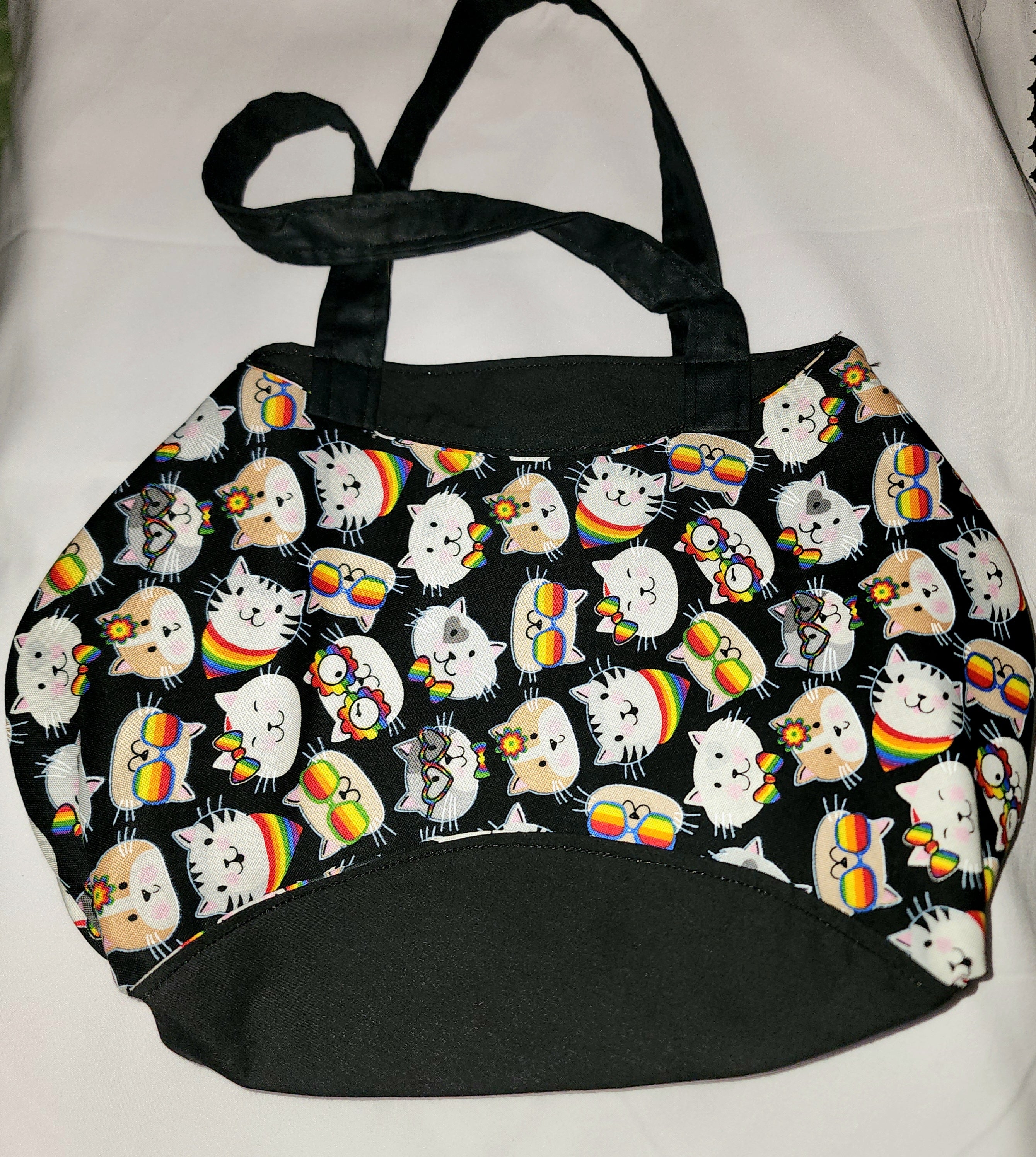 Black tote bag with cat pattern featuring rainbow elements on a white background