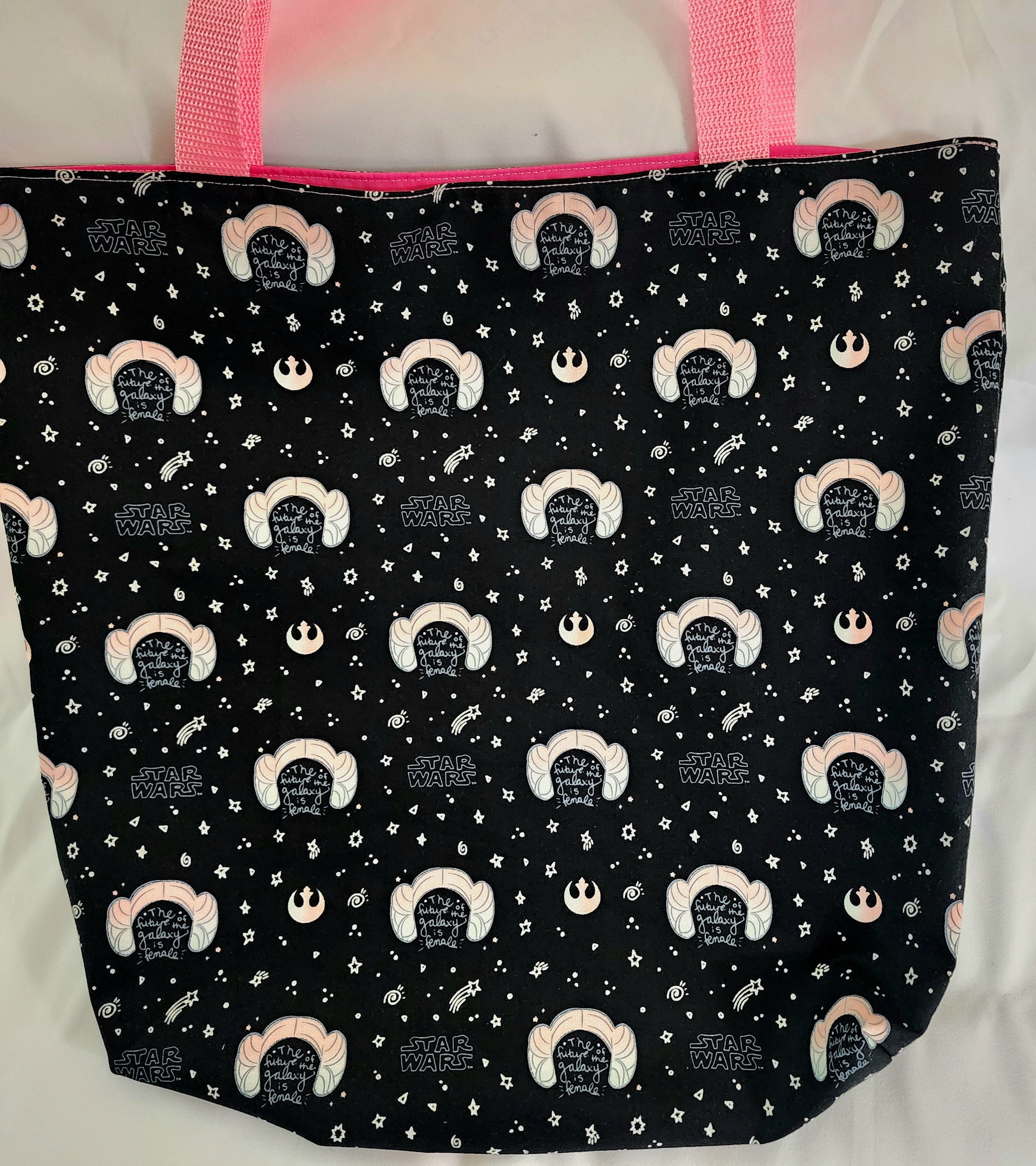 Black tote bag with white and pink patterns on a white background
