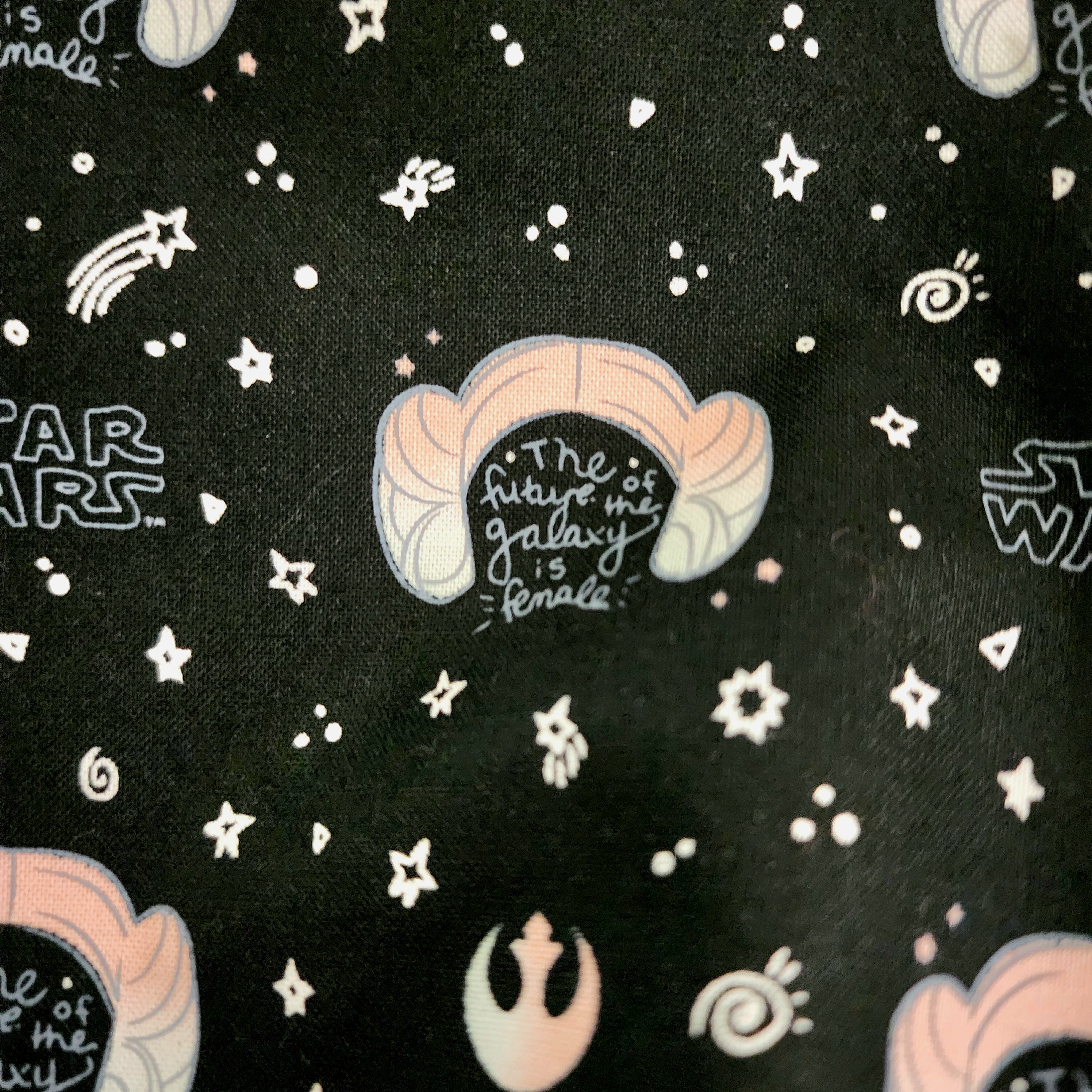 Tote closeup 'The Future of the Galaxy is Female" text on a black fabric background with star patterns