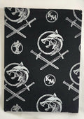 Black fabric with white wolf and sword pattern on a white background