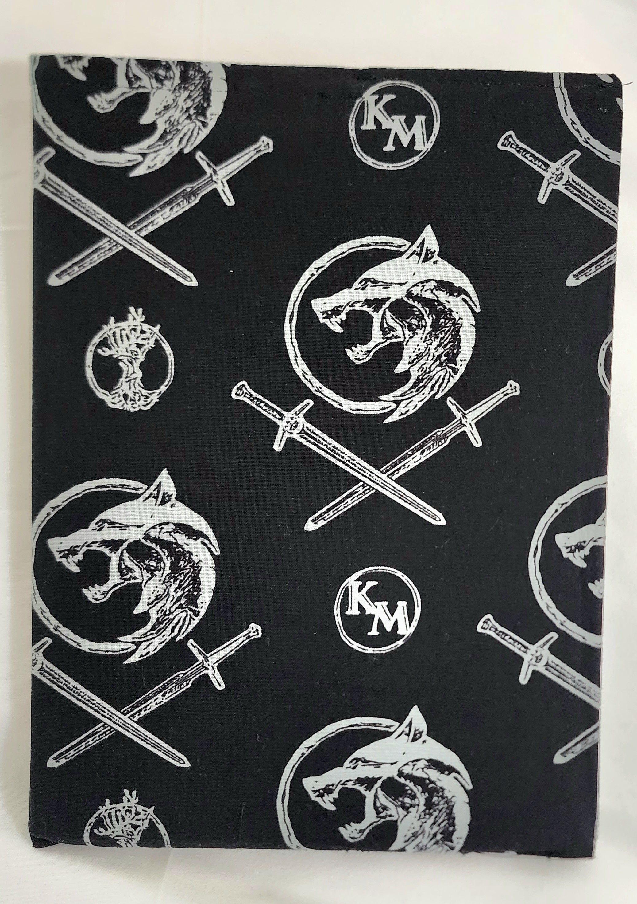 Black fabric with white wolf and sword pattern on a white background