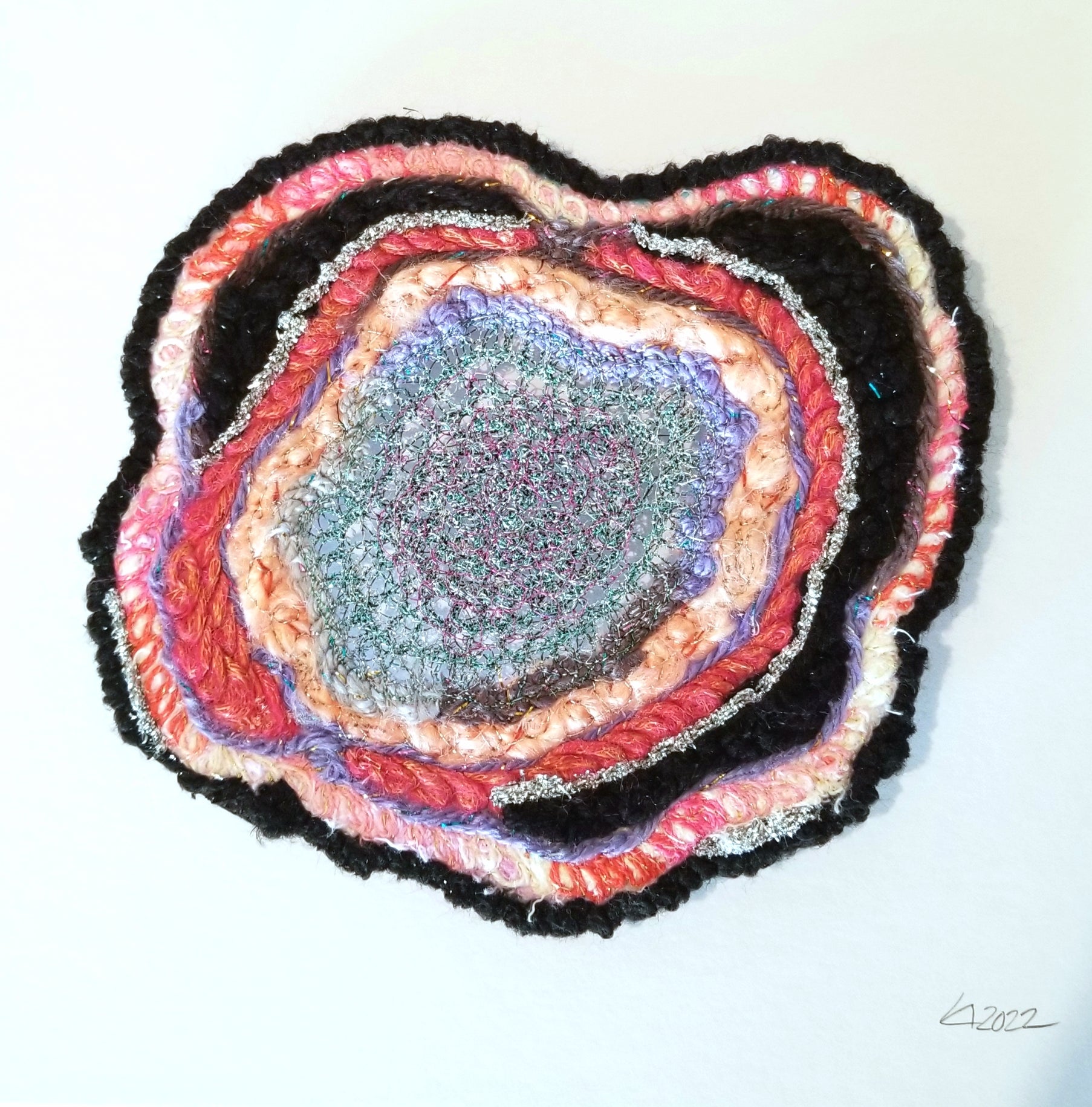Colorful woven circular art piece on a white background