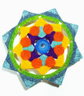 Colorful crocheted star-shaped object with a blue center on a white background