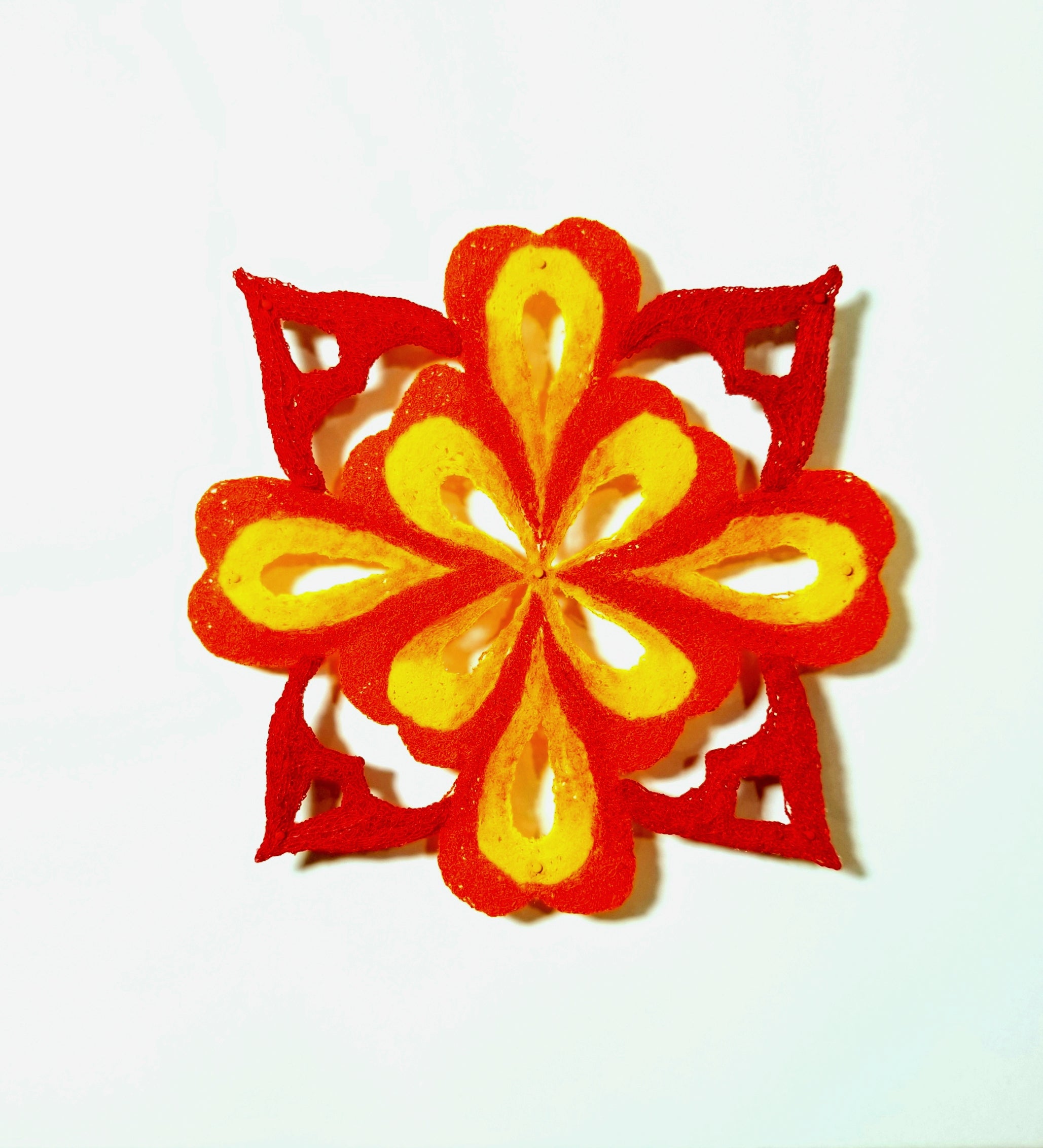 Decorative flower-shaped object with red and yellow colors on a white background