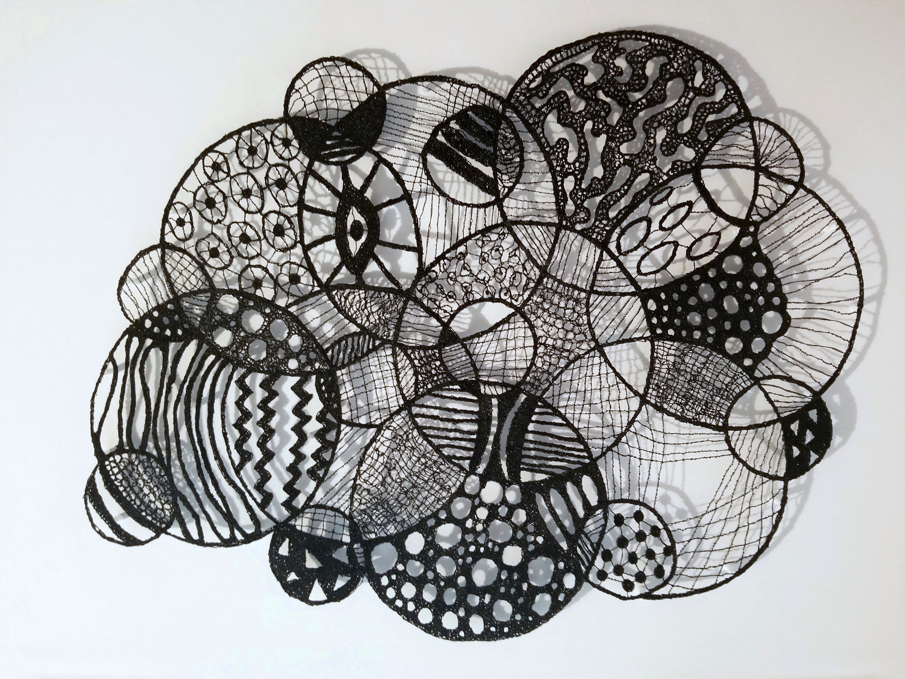Black and white abstract circular patterns made entirely of thread on a white background