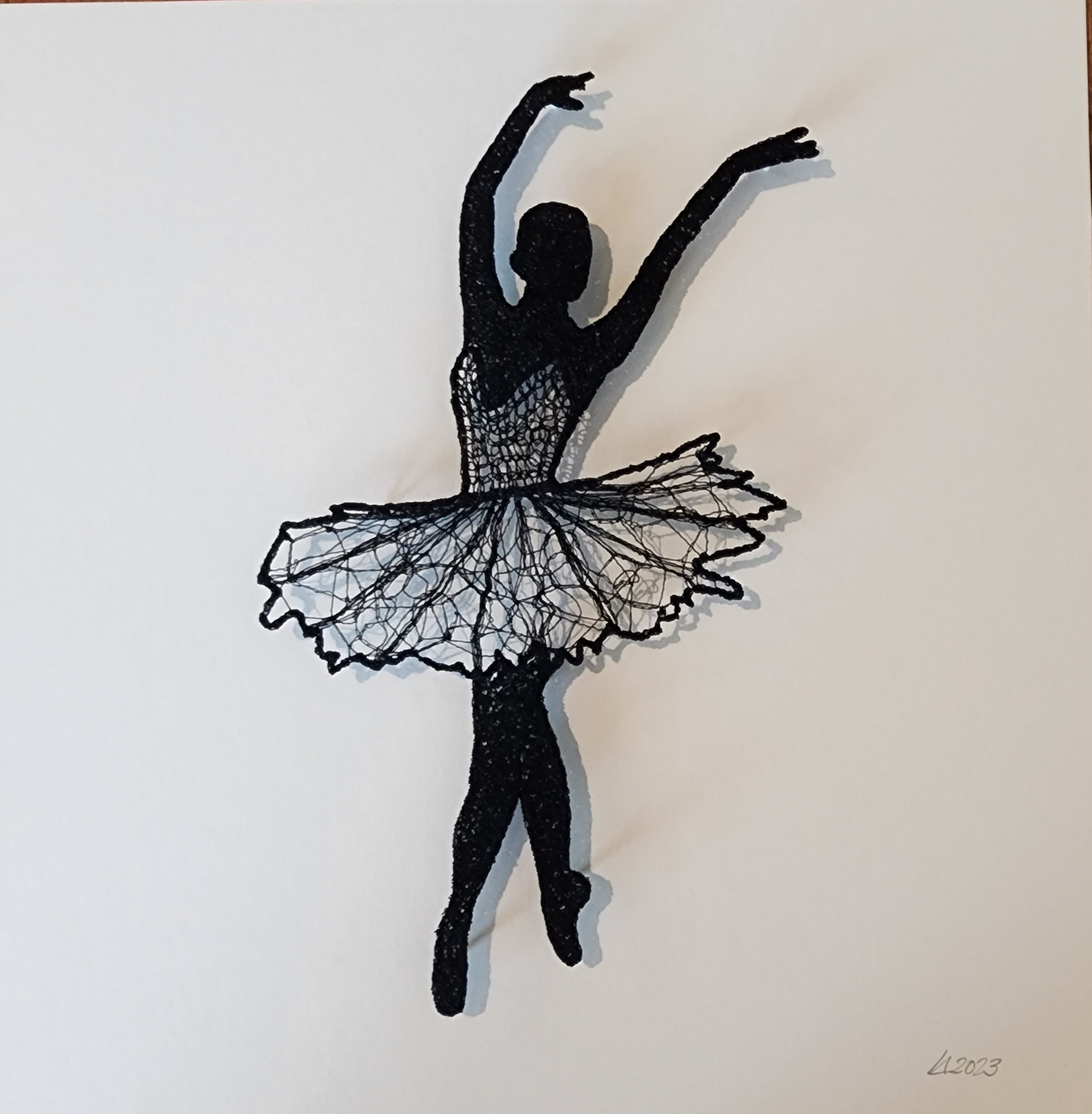 Black thread sculpture of a ballerina on a white background