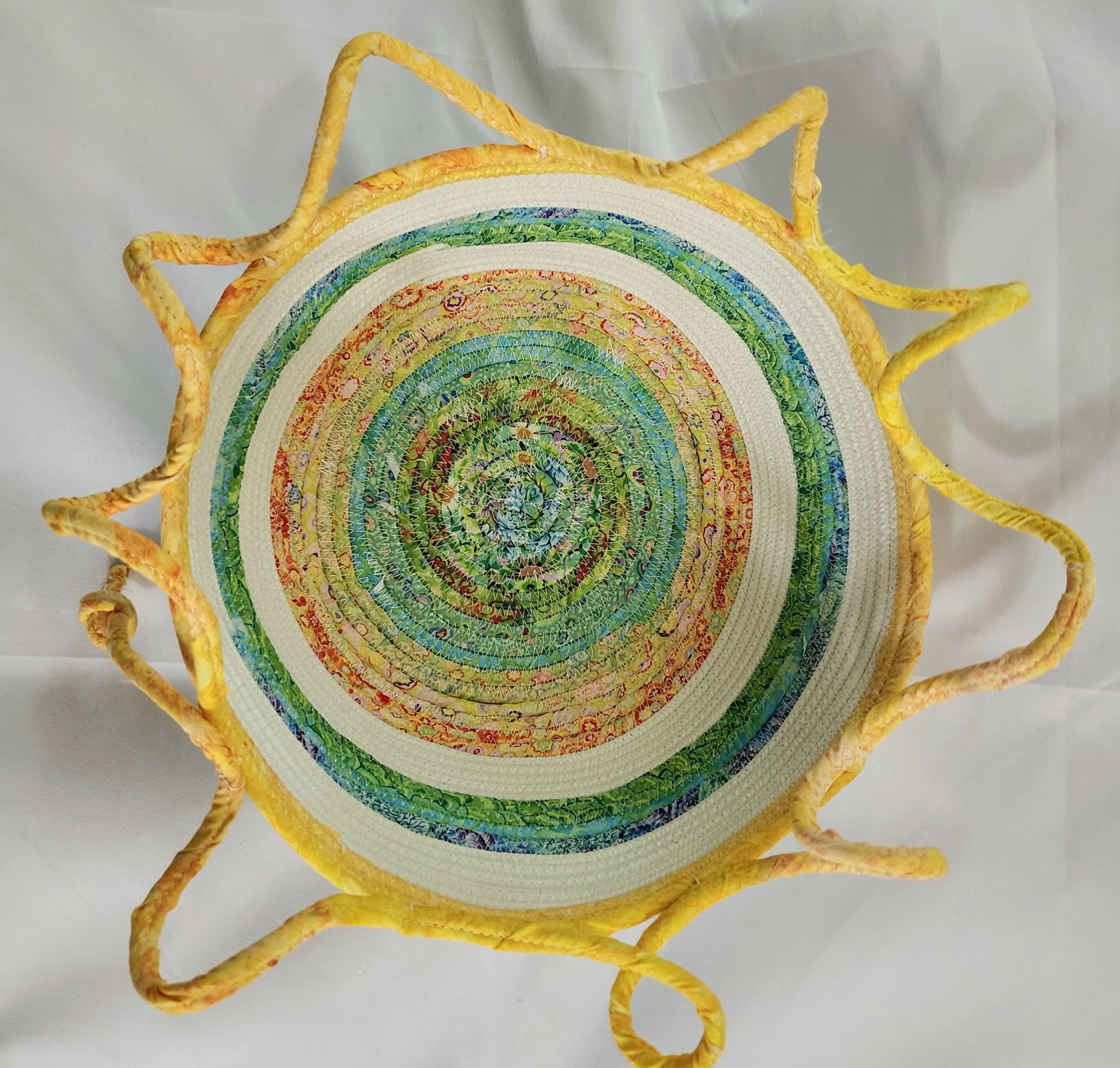 Decorative woven bowl with concentric circles and yellow rim on a white background