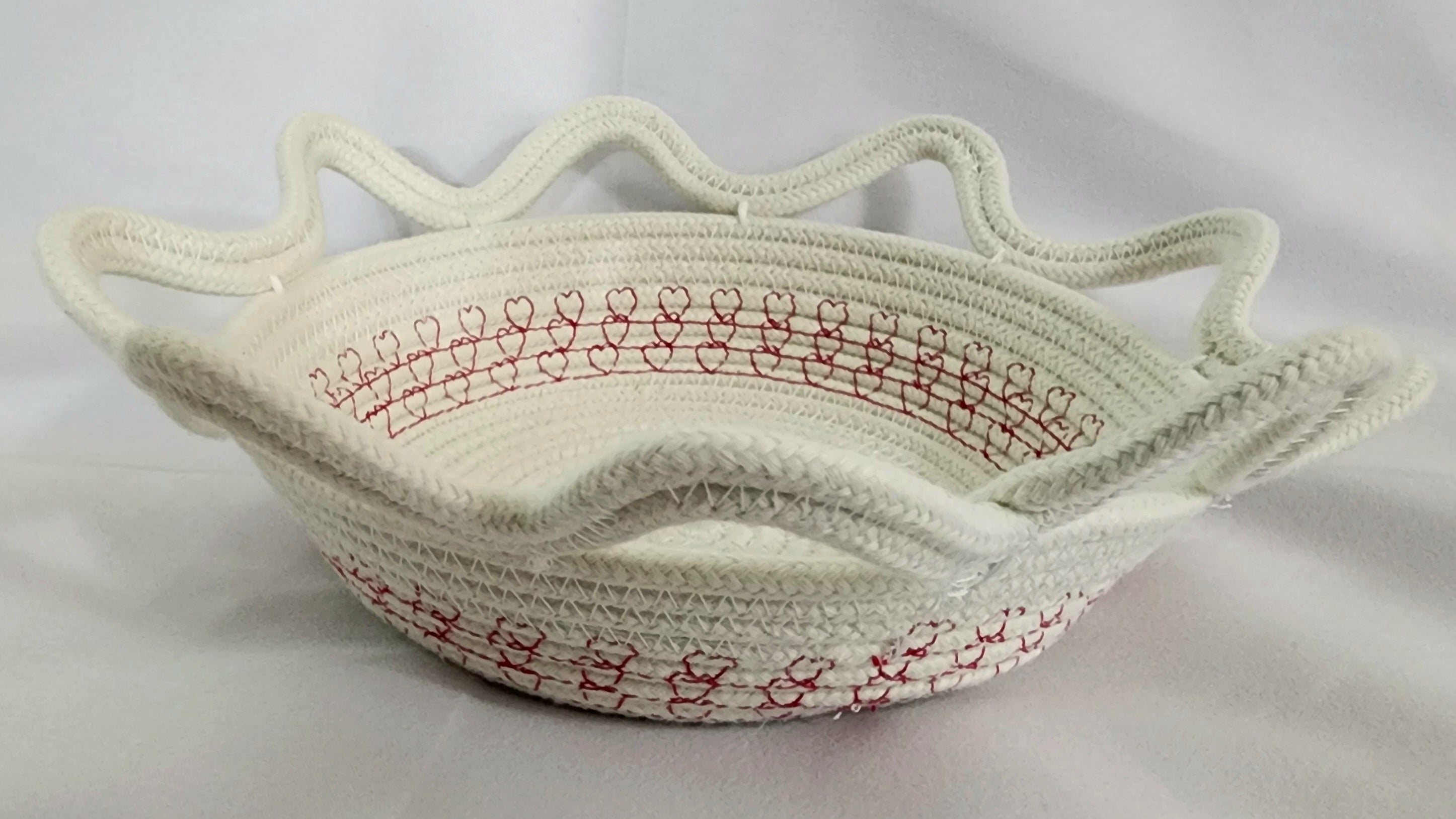 White woven basket with red stitching on a white background