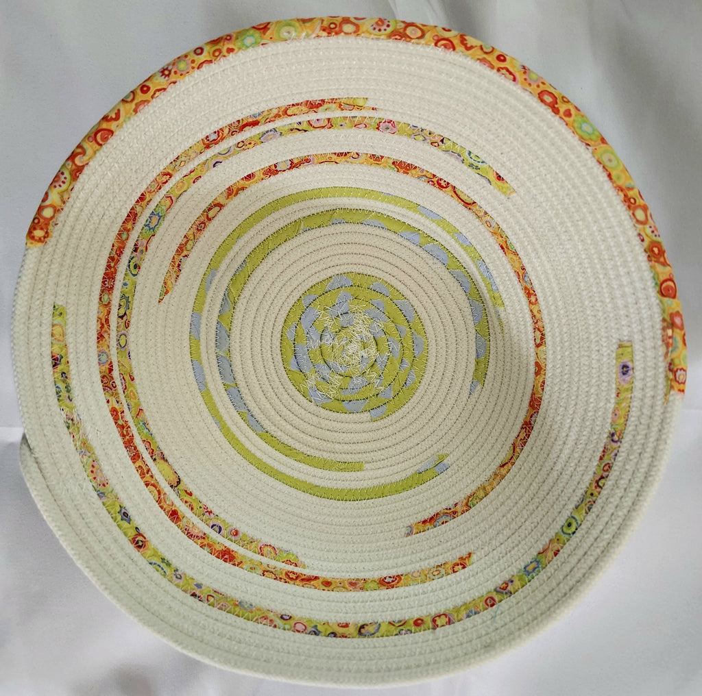 Round woven bowl with colorful concentric circles on a white background